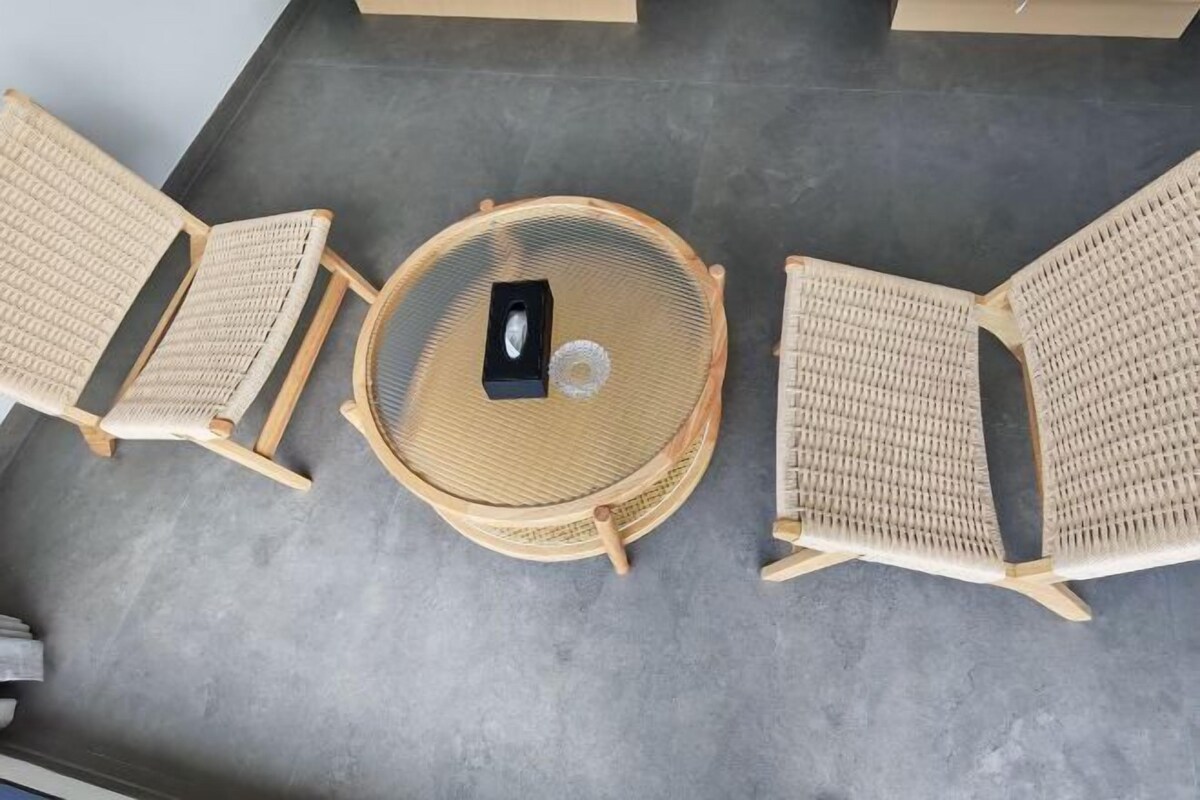 Vista cenital de una habitación con una mesa redonda y dos sillas de mimbre.