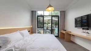 Ein Hotelzimmer mit Bett, Schreibtisch, Fernseher und einem Balkon mit Blick.