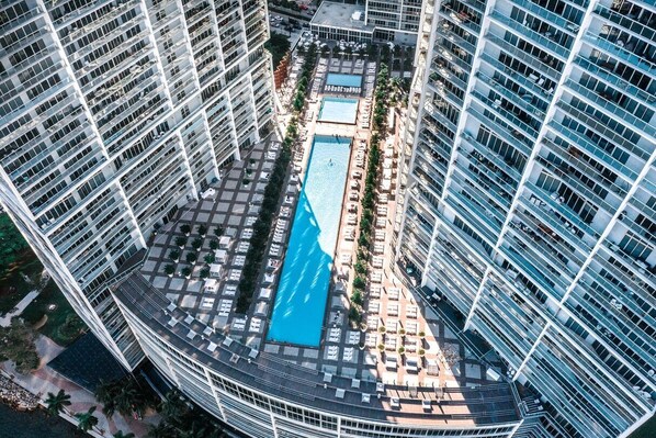 A high-rise building with a rooftop pool surrounded by lounge areas and sunbeds. - ICON W BRICKELL MAGNIFICENT RIVER VIEW 2BR/2BA #2102 (Miami)
