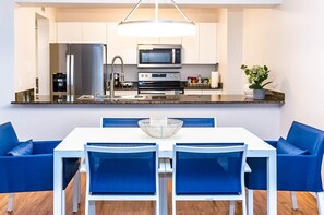 A modern kitchen with stainless steel appliances, a dining table with blue chairs, and a potted plant on the counter. - Brickell 1BR • City Views • Balcony • FREE Parking • Pool • Hot Tub • Gym (Miami)