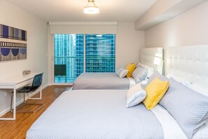 A modern hotel room with two beds, a desk, and a large window offering a view of high-rise buildings. - Brickell 1BR • City Views • Balcony • FREE Parking • Pool • Hot Tub •Gym (Miami)