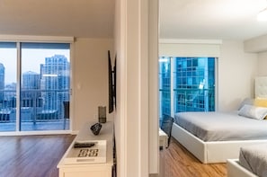 A modern bedroom with a city view, a bed, a nightstand, and a large window. - Brickell 1BR / City Views / Balcony / FREE Parking / Pool / Hot Tub / Gym (Miami)
