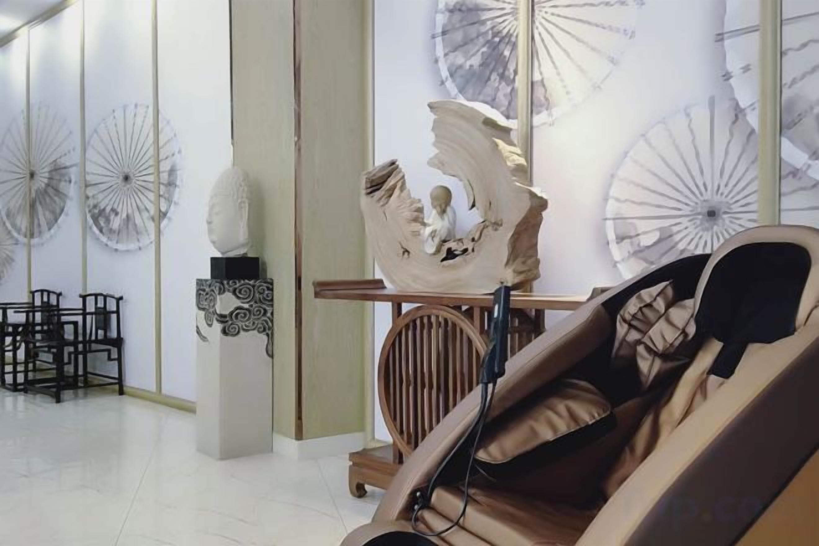 A room with a massage chair, a table with a decorative item, and wall-mounted umbrellas.