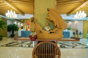 A lobby with a large wooden sculpture, a reception desk, and a patterned floor.
