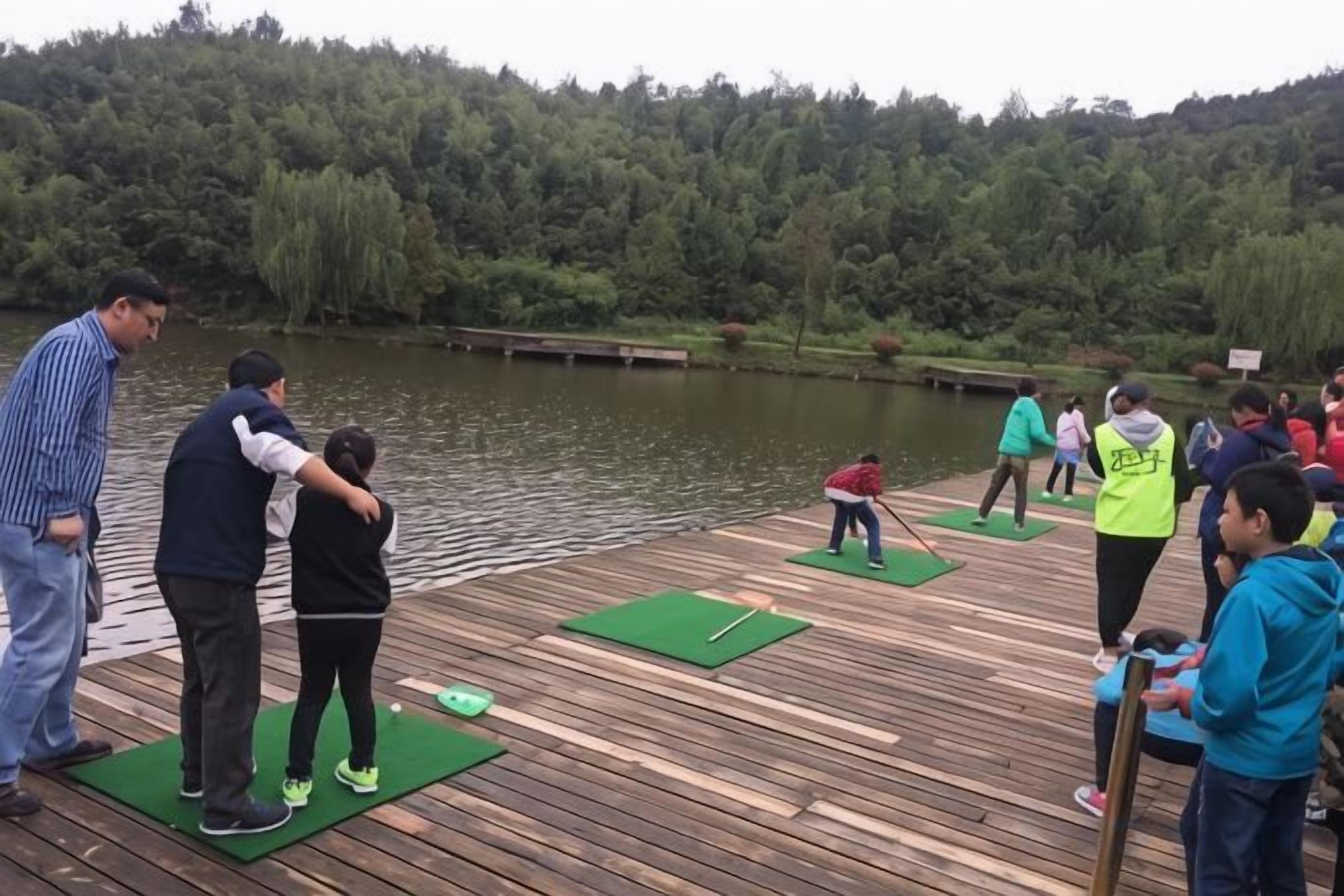 A wooden dock with people engaging in activities, surrounded by a lake and forested hills.