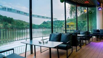 An outdoor seating area with tables and chairs, overlooking a body of water and a distant building.