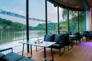 Un espacio al aire libre con mesas y sillas, con vista a un cuerpo de agua y un edificio distante.