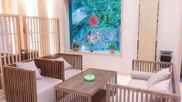 A room with a wooden sofa set, a small table, and a window with a view of a rock garden.