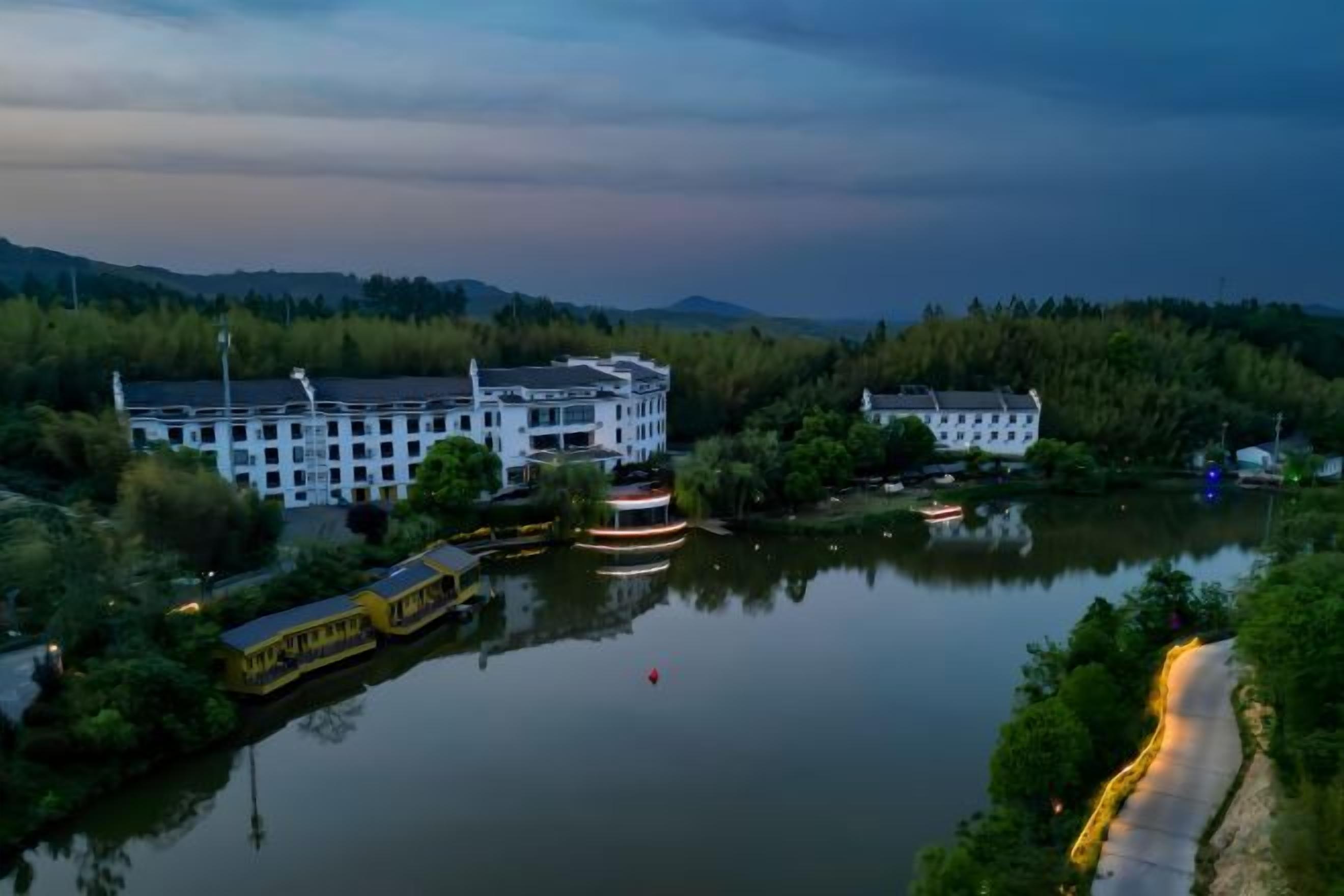 Un hôtel situé au bord de la rivière, doté d’un quai pour bateaux et entouré de verdure et de collines.