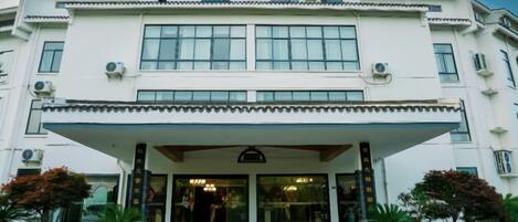 A two-story building with a covered entrance, large windows, and a symmetrical facade.
