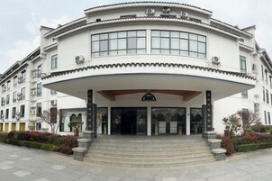 Un edificio de varios pisos con fachada curva, ventanas amplias y una entrada central con escalones de acceso.