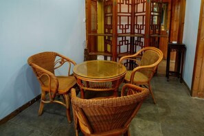 A room with a round table and four wicker chairs, a small side table, and a traditional wooden screen. - Liyang Nanshan Zhuhai Cuigu Manor Hotel (Liyang)
