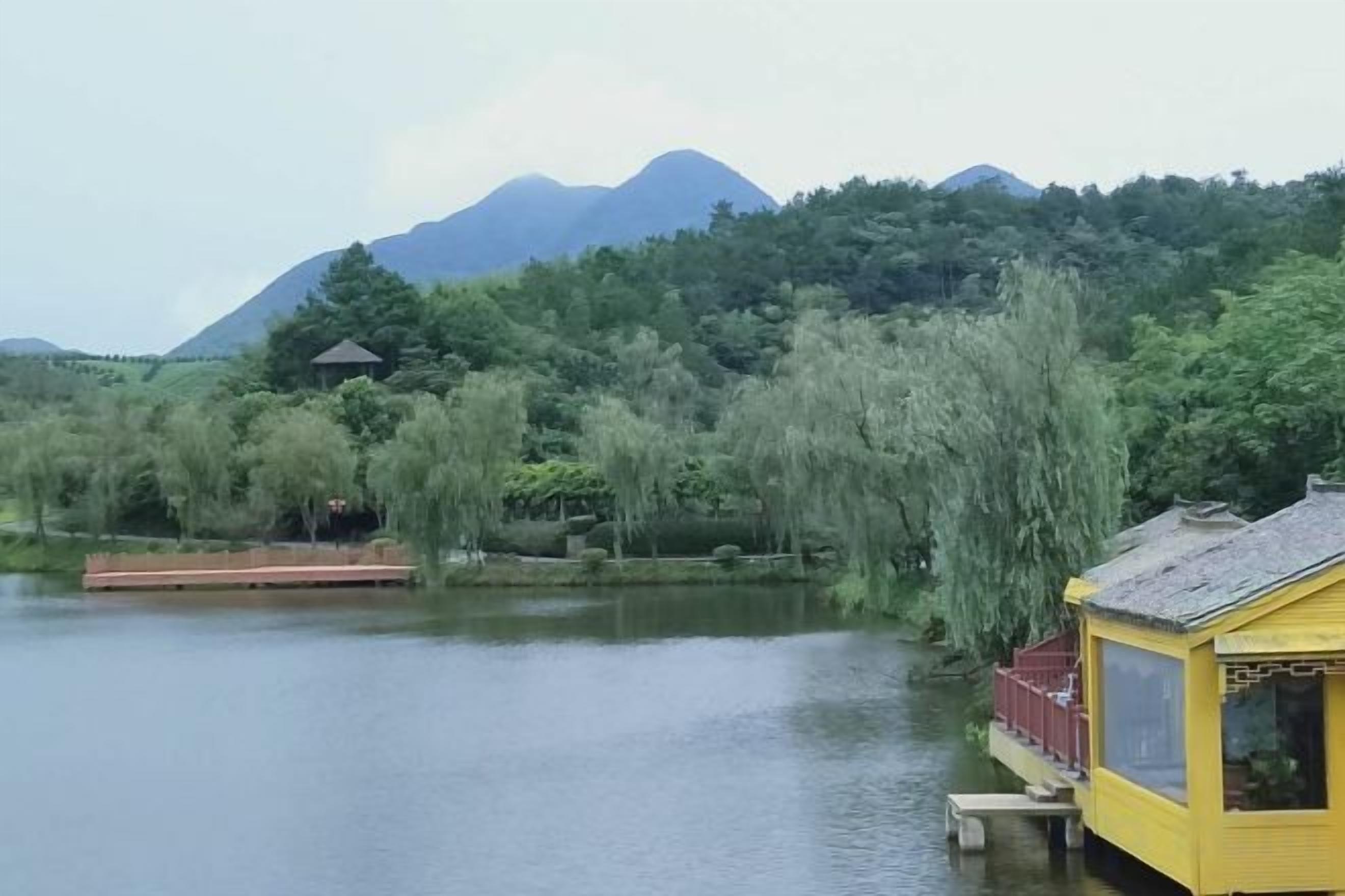 A riverside view with a wooden dock, a yellow building, and a mountain in the background.