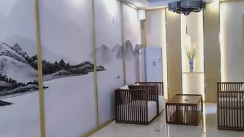 A room with a mural of mountains, a bed, a bedside table, and a hanging light fixture.