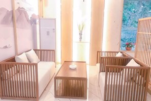 A room with a sofa, a table, and two chairs with slatted designs. - Liyang Nanshan Zhuhai Cuigu Manor Hotel (Liyang)