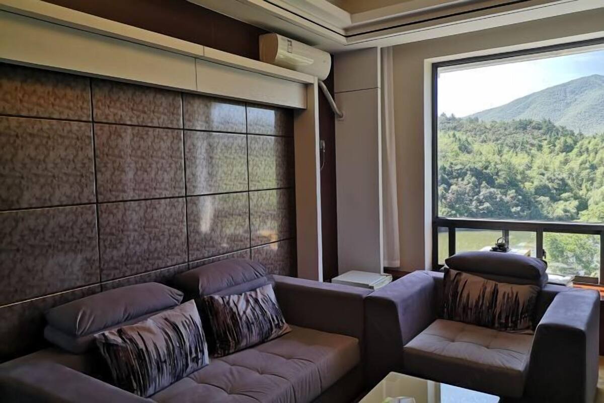 A modern living room with a large window, a sofa, and a chair.