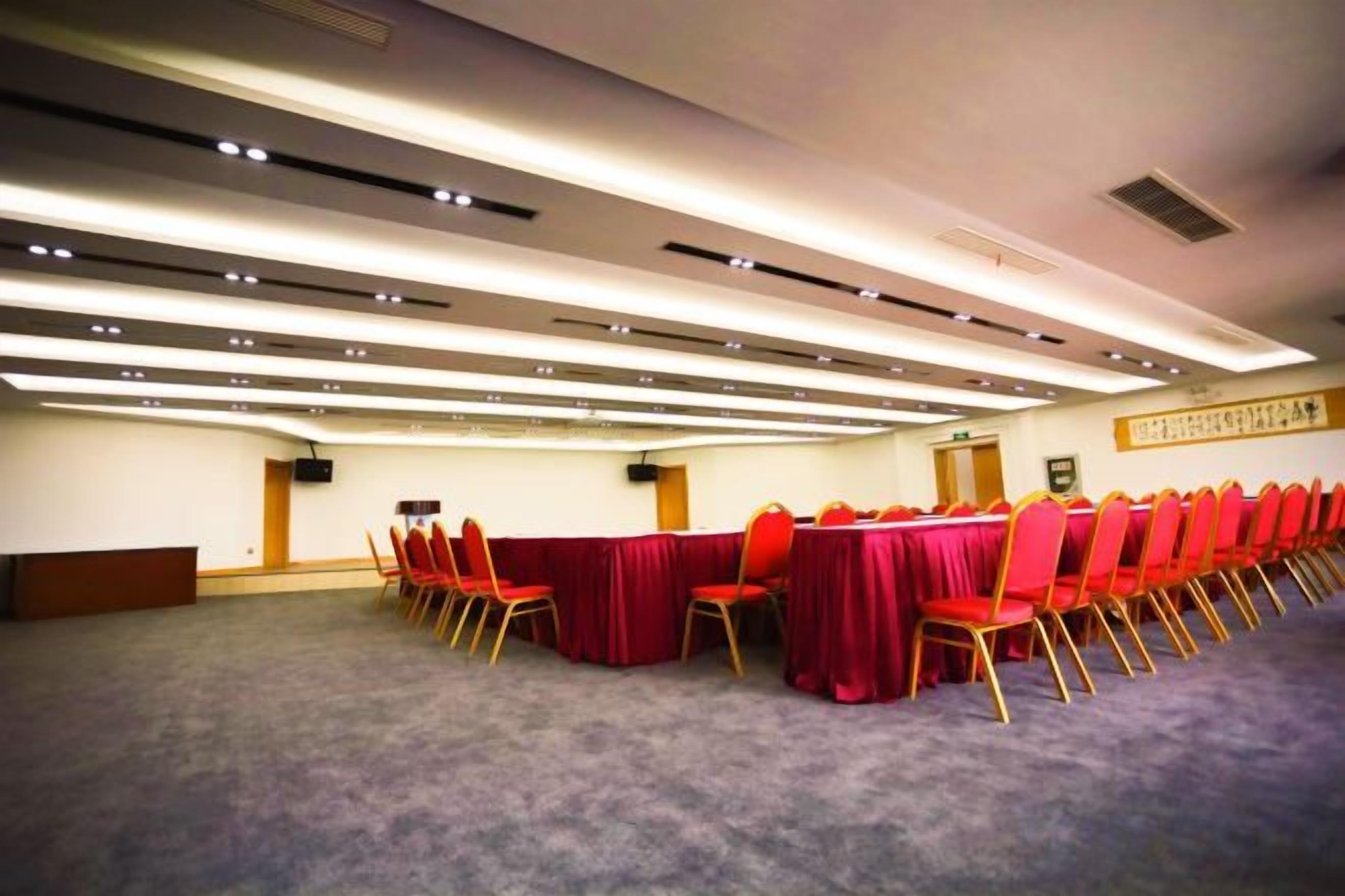 A conference room with a long table, red chairs, and a carpeted floor.