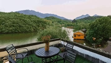 A terrace with outdoor seating and a view of a river and mountains.