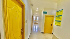 A hotel hallway with yellow doors, a clean floor, and a sign on the wall. - Yingjia Chain Hotel (Dongguan Xiaobian) (Dongguan)