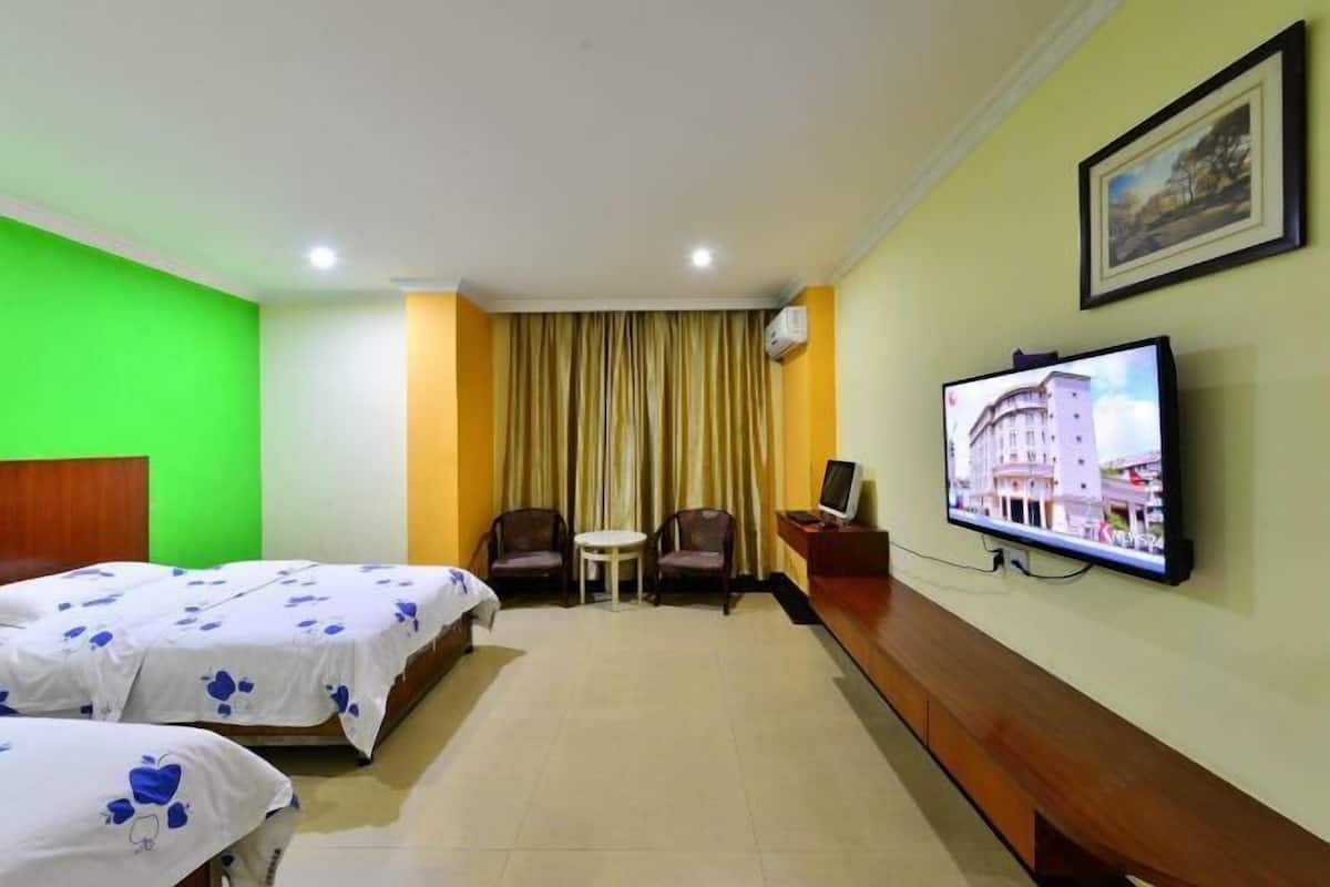 A hotel room with two beds, a television, a small table, and a chair.