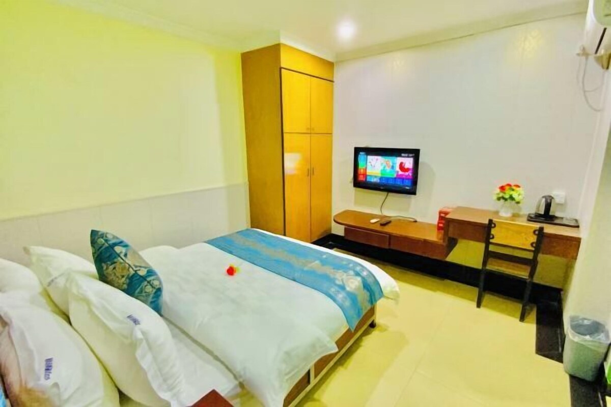 Een hotelkamer met een bed, een bureau, een stoel, een televisie en een kledingkast.