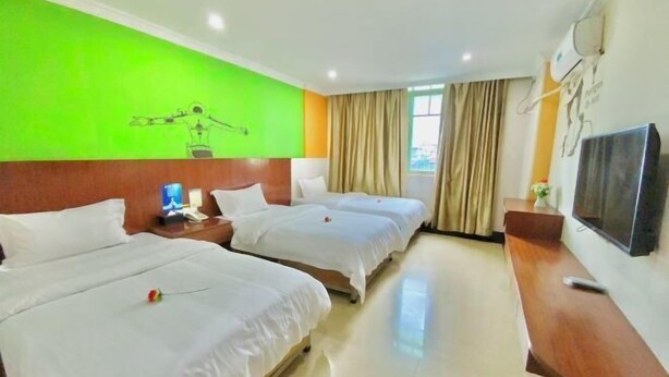 A hotel room with three beds, a wooden desk, a flat-screen TV, and a green wall with a drawing. - Yingjia Chain Hotel (Dongguan Xiaobian) (Dongguan)