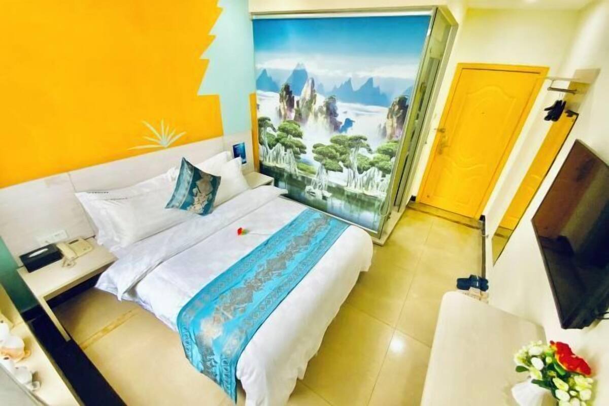 A hotel room with a bed, a nightstand, a TV, and a door.