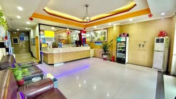 A hotel lobby with a reception desk, seating area, and vending machines.