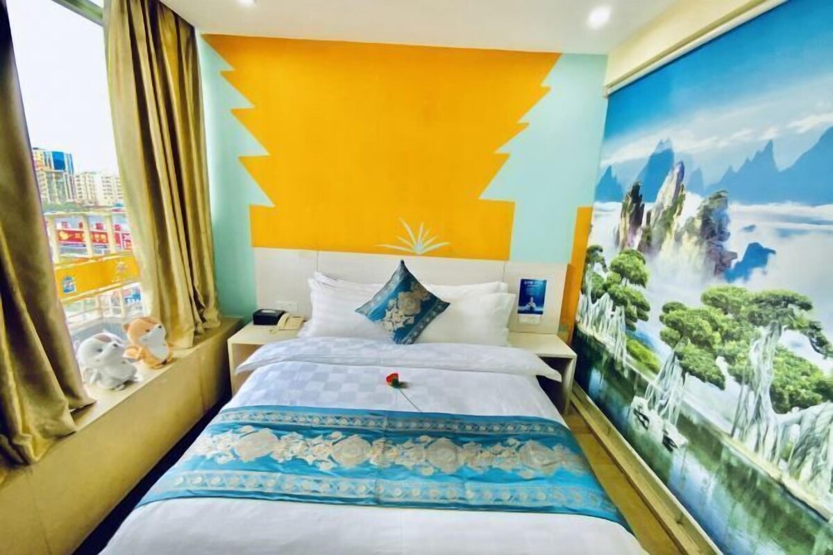 Een hotelkamer met een bed, een nachtkastje, een raam met gordijnen en een muurschildering.