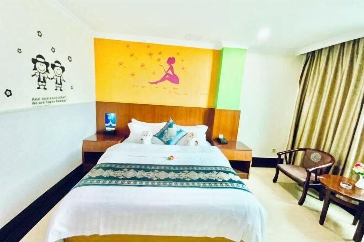 Een hotelkamer met een bed, nachtkastjes, een stoel en een muur met een muurschildering.