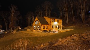 Una cabaña de madera con porche, ventanas grandes y cimientos de piedra.