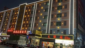 A multi-story hotel with illuminated windows and a signboard advertising a restaurant. - Yinhong Hostel (Kaiping)