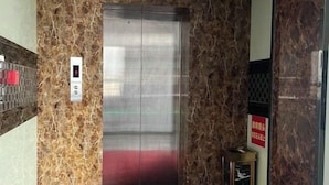 An elevator with a marble wall and a digital display showing the number 3. - Yinhong Hostel (Kaiping)