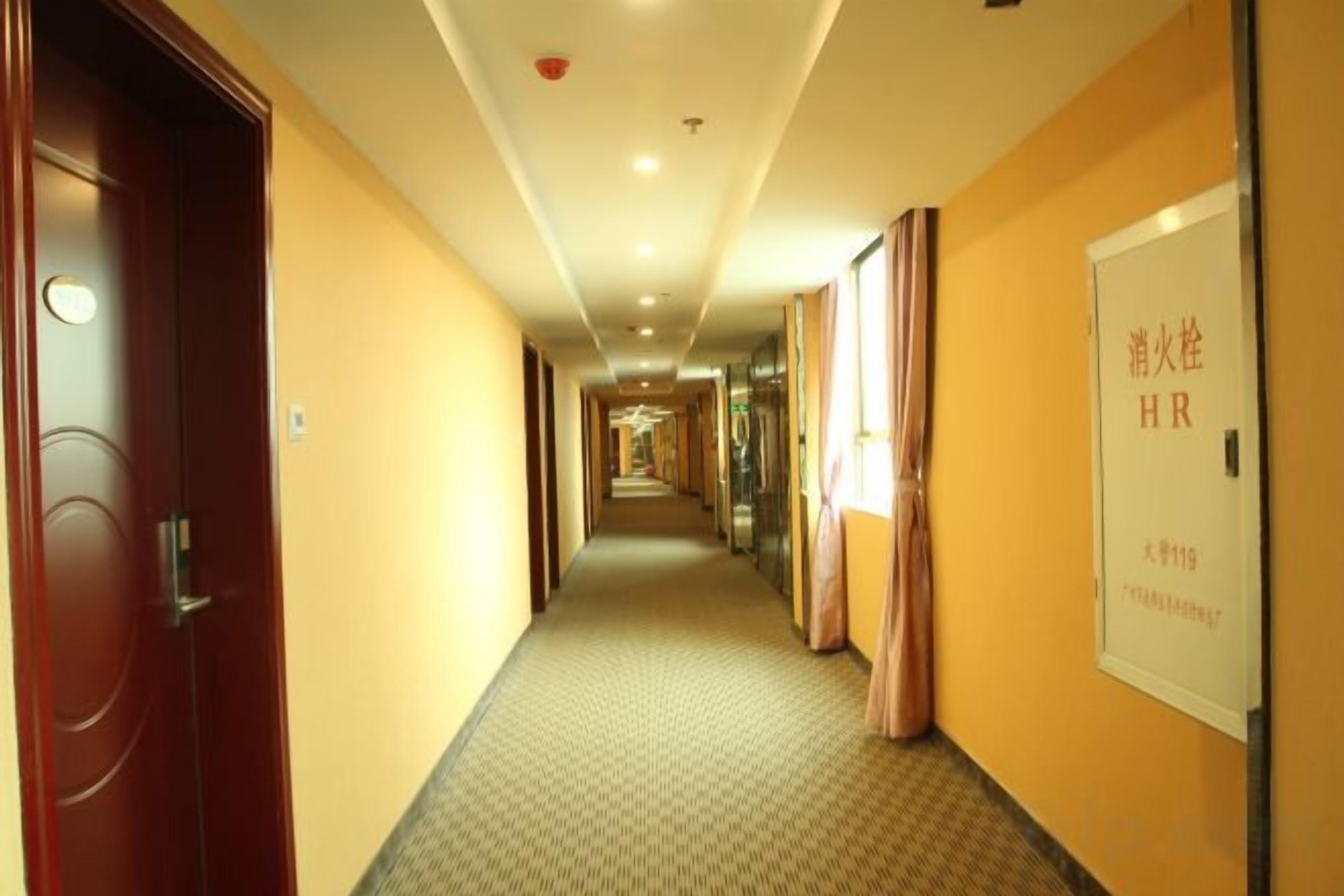 Un pasillo de hotel con puertas a la izquierda, un cartel a la derecha y suelo cubierto de alfombra.