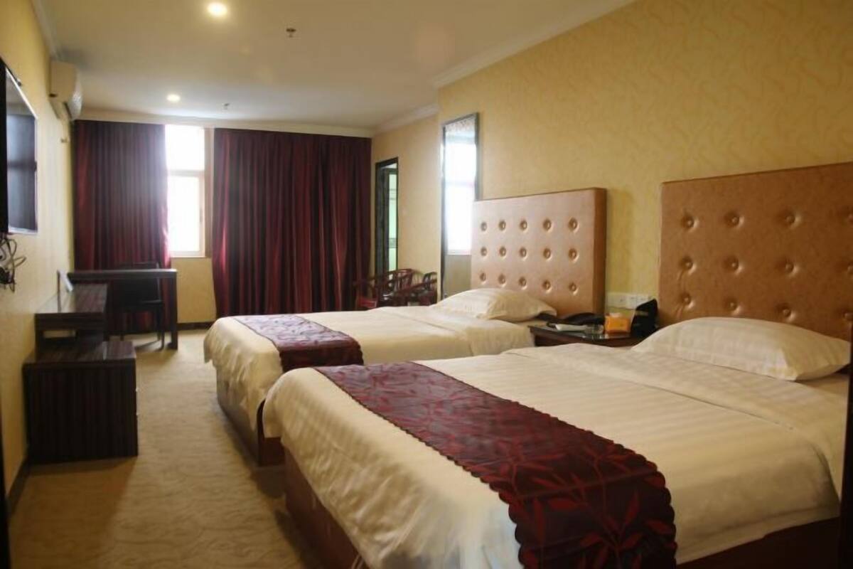 A hotel room with two beds, a desk, and a chair.