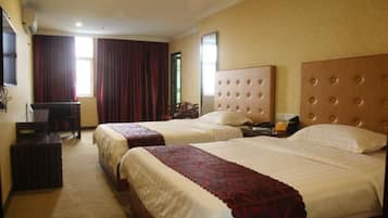A hotel room with two beds, a desk, and a chair.