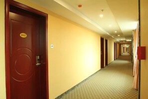 A hotel corridor with doors, a carpeted floor, and a ceiling with recessed lighting. - Yinhong Hostel (Kaiping)