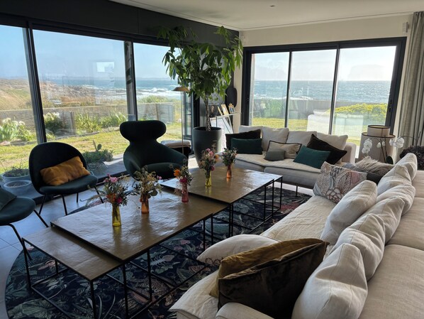 A modern living room with a large window, a sofa, a coffee table, and a chair.