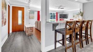 Una sala de estar moderna con piso de madera, un banco integrado, un sofá y un comedor con sillas y mesa de madera.