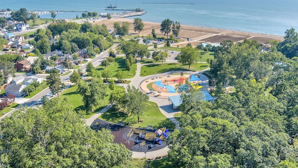 Un parque costero con áreas de juego, senderos peatonales y una playa.