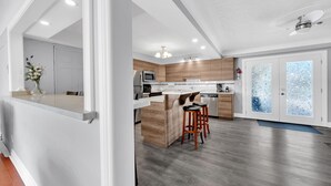 Una cocina moderna con armarios de madera, electrodomésticos de acero inoxidable y una zona de bar con taburetes.