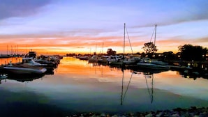 Una marina con barcos amarrados en aguas tranquilas que reflejan el cielo al atardecer.