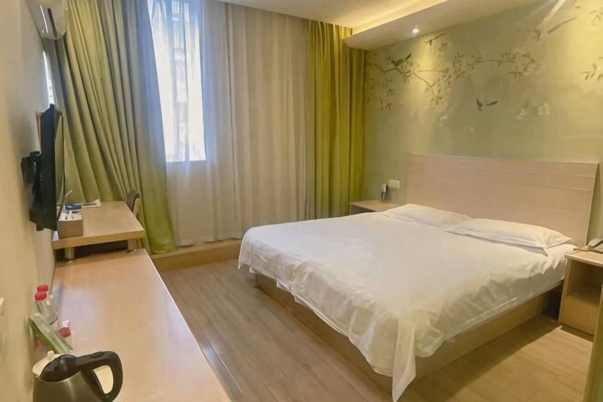 Una habitación de hotel con cama, mesita de noche y escritorio con silla.