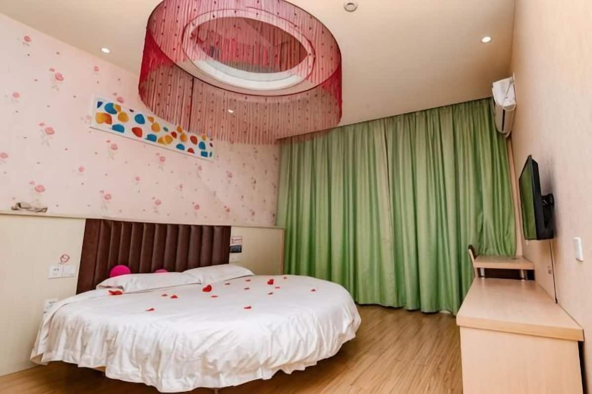 Un dormitorio con cama, escritorio, televisor y una lámpara de techo circular.