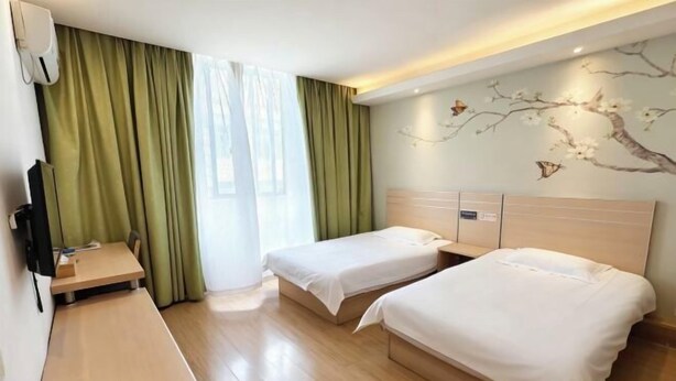 Habitación de hotel con dos camas, un escritorio, un televisor y una ventana con cortinas.