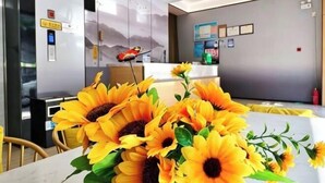 Un moderno hall de hotel con una recepción, un cartel en la pared y un arreglo decorativo de girasoles.