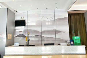 A reception desk with a view of mountains through a patterned wall, a flat-screen TV, and a security camera.