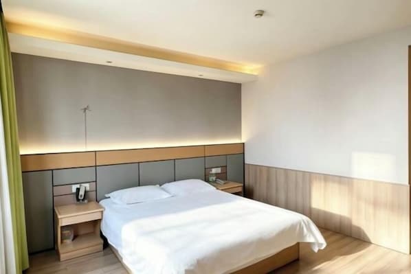 A modern hotel room with a large bed, bedside tables, and a headboard with built-in lighting.