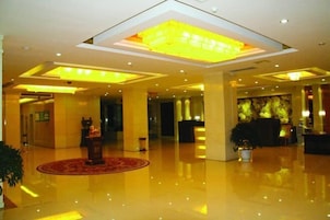 A spacious lobby with a polished floor, a reception desk, and a large illuminated ceiling feature.