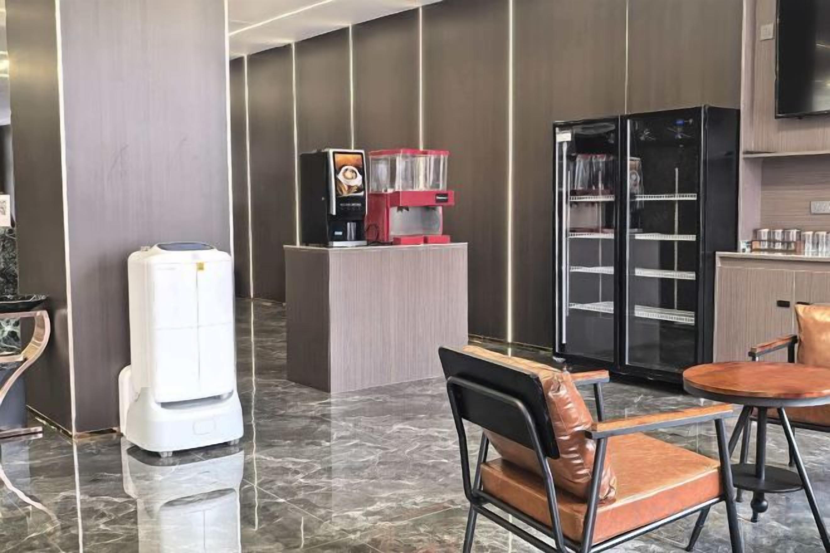 A hotel lobby with a reception desk, seating area, and a refrigerator.